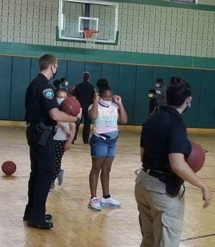 A Niagara County, New York, police officer playing basketball with a group of kids.