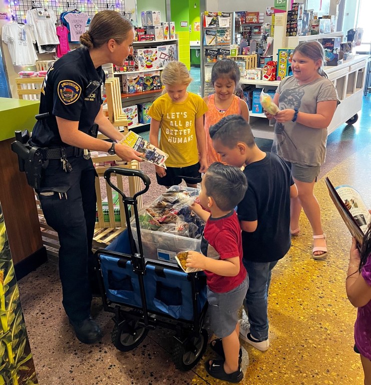 An image of a Sioux City, Iowa, police officer handing out books to children in the community.