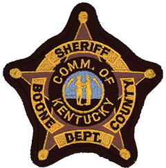 The patch of the Boone County, Kentucky, Sheriff’s Office depicts two men, one in buckskin and the other in more formal dress, facing each other and clasping hands. This represents the state motto, “United we stand, divided we fall.” Popular belief identifies the buckskin-clad man as Daniel Boone, largely responsible for the exploration of the state, and the man in the suit as Henry Clay, Kentucky’s most famous statesman. However, according to the official explanation, the men represent all frontiersmen and statesmen, rather than specific persons.