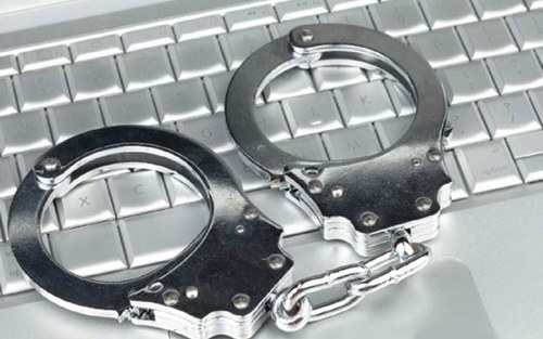 Stock image of a pair of handcuffs on a computer keyboard.