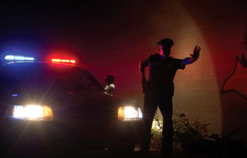 Cop in Front of Cruiser at Night