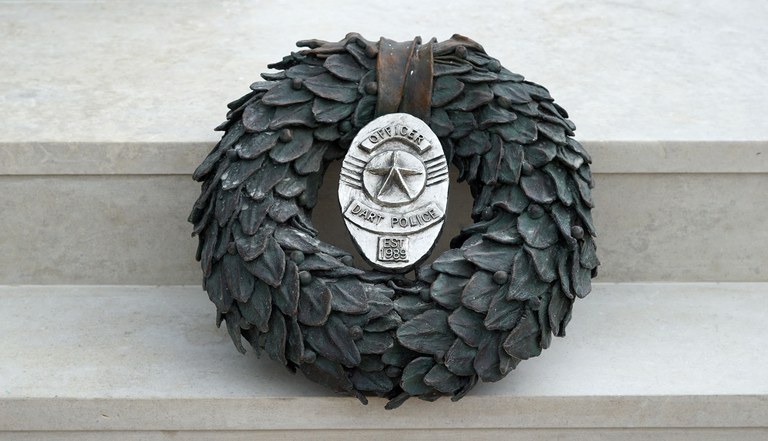 A wreath with a badge in the center located on the stairs of the 7|7 Monument, Dallas, Texas.