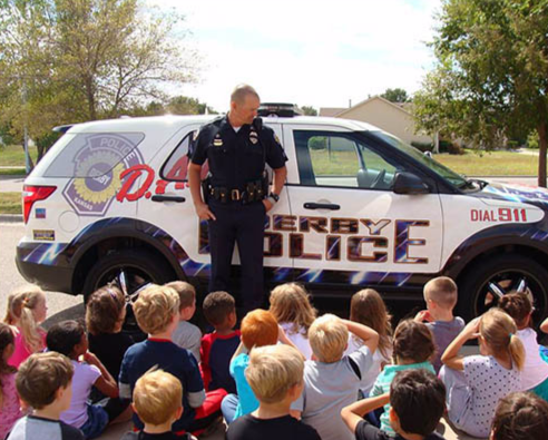 A police officer discusses the dangers of drug use with a group of students.