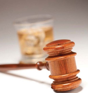 Gavel with Glass of Whiskey in Background (Stock Image)