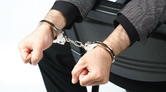 Stock image of a man in handcuffs with his arms over the back of a chair.
