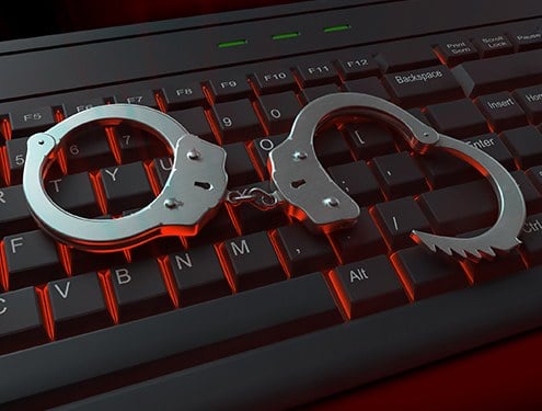 Stock image of a pair of handcuffs sitting on top of a black keyboard.