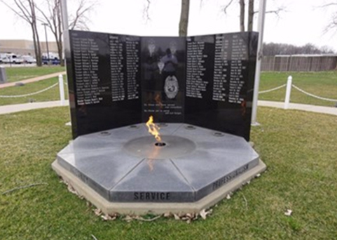 The Indiana State Police Memorial, located on the east side of Indianapolis, consists of three black granite tablets and an eternal flame.