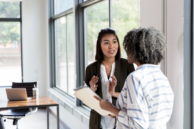 A stock image of two female co-workers talking.
