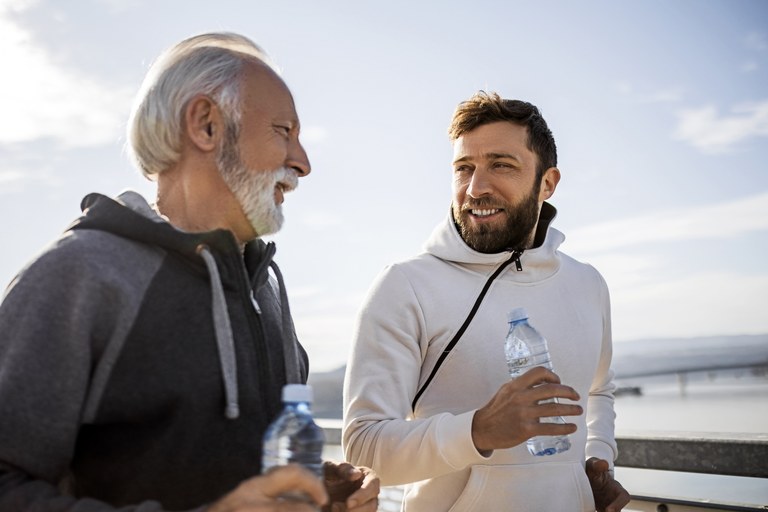 An stock image of an older man and younger man walking together and talking.