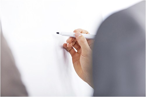 Stock image of a person with a marker preparing to write on a whiteboard.