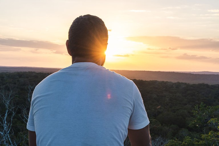 A stock image of a man looking at the sunrise.