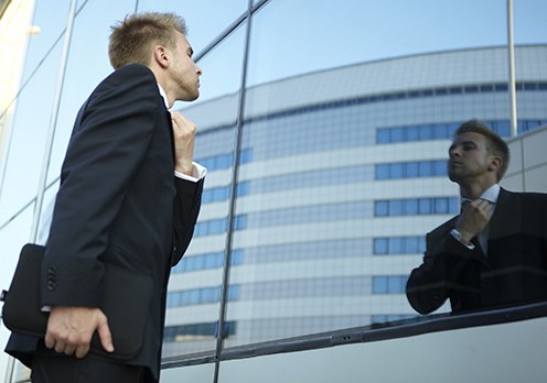 Man Fixing Tie Using Glass Building as Mirror (Stock Image)