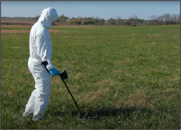 A photo of an scientist using a metal detector.
