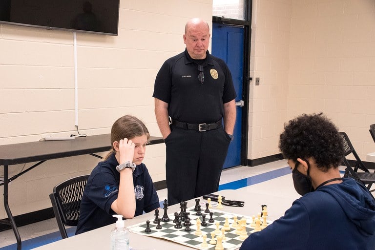 New Bern Police Chief watching two teens play a game of chess.