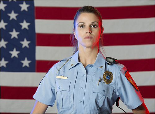 Female Police Officer in Front of American Flag (Stock Image)