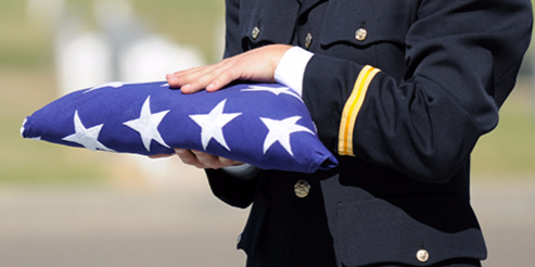 A police officer holds an American flag at a memorial service.