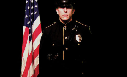 Officer Standing by American Flag
