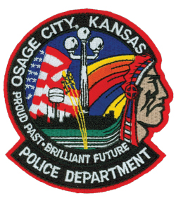 The patch of the Osage City, Kansas, Police Department prominently references the city’s proud past and brilliant future. One of the city’s famous 6th Street light poles is shown in the center, followed below by strands of wheat, a well-known staple in Kansas. The background depicts a flowing American flag symbolizing national pride, as well as the city skyline with its large water tower. To the right is a representation of the Osage Indian, after which the city is named.