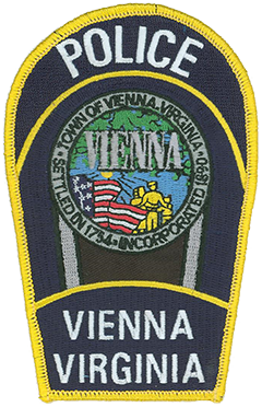 The town of Vienna, Virginia, is located approximately 12 miles east of Washington, D.C., and is home to over 15,000 residents. Incorporated in 1890, the area comprising the town first was permanently settled in 1754. The patch of the Vienna Police Department features the town seal at its center, which depicts a family looking forward with hopeful vision, brightened by a radiant sunrise. Above them is foliage from one of Vienna’s many tree-lined streets, and behind them is the American flag.