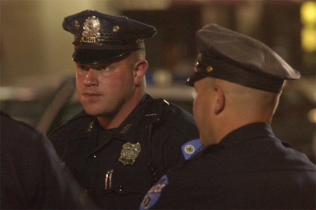 Two police officers interact at the scene of an incident.
