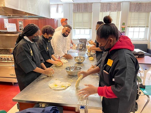 A picture of a group of young adults working in a kitchen.
