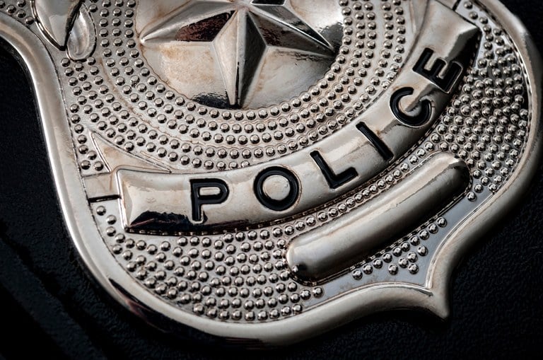 A stock image of a silver police badge on a black background.