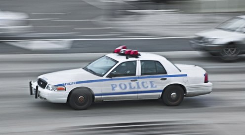 A police car driving at high speed on a highway. 