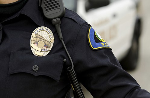 Stock image of a police officer in uniform showing a badge and patch.