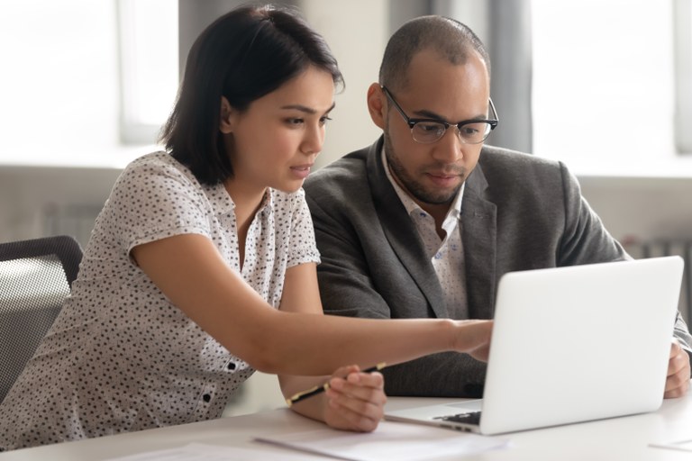 A stock image of two business people working together on a computer.