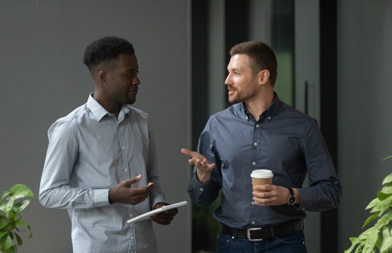 A stock image of two men talking in an office environment.