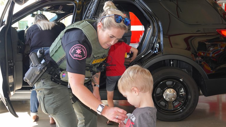 A stock image of a female officer putting a sticker on the shirt of a young boy.