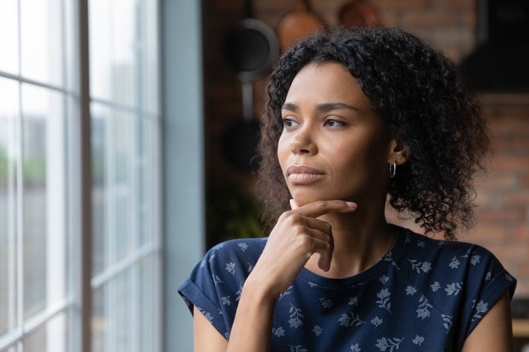 A stock image of a female looking out a window.