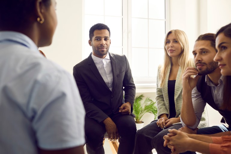 A stock image of a male talking to a group of people.