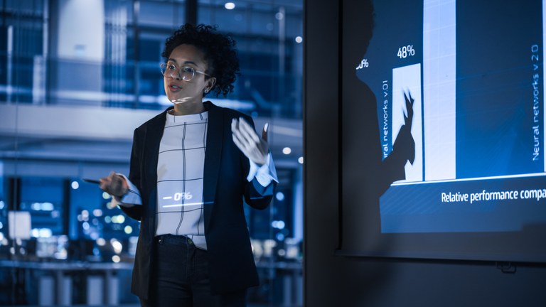 A stock image of a business women showing a slide during a presentation.