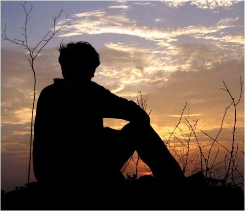 Silhouette of Person Sitting on Ground Watching Sunset (Stock Image)