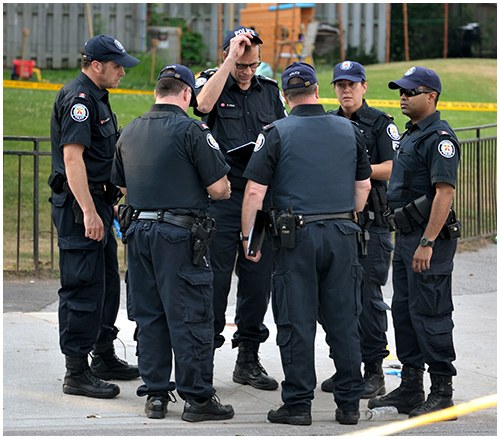 A group of six police officers standing in a circle discussing an issue.