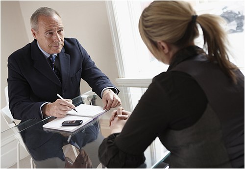 Stock image of a businessman interviewing a woman for a job in an office.