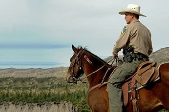 Photo by California Department of Fish and Wildlife, of a wildlife officer in uniform sitting on his horse