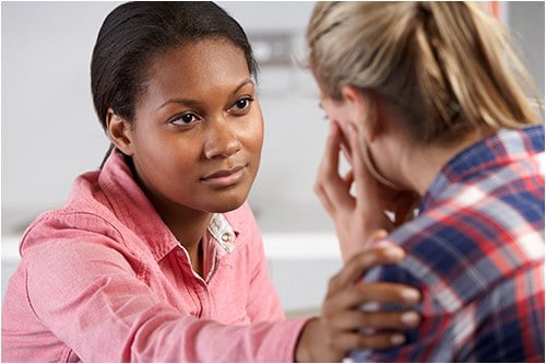 Stock image of a woman consoling a female victim.