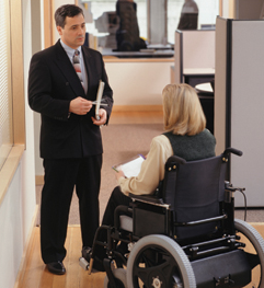 Woman in Wheelchair Talking to Colleague (Stock Image)