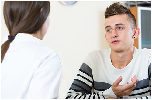 A young man talking to a social worker or other professional.
